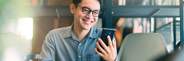 Homem sorrindo enquanto segura e olha para um dispositivo Android.